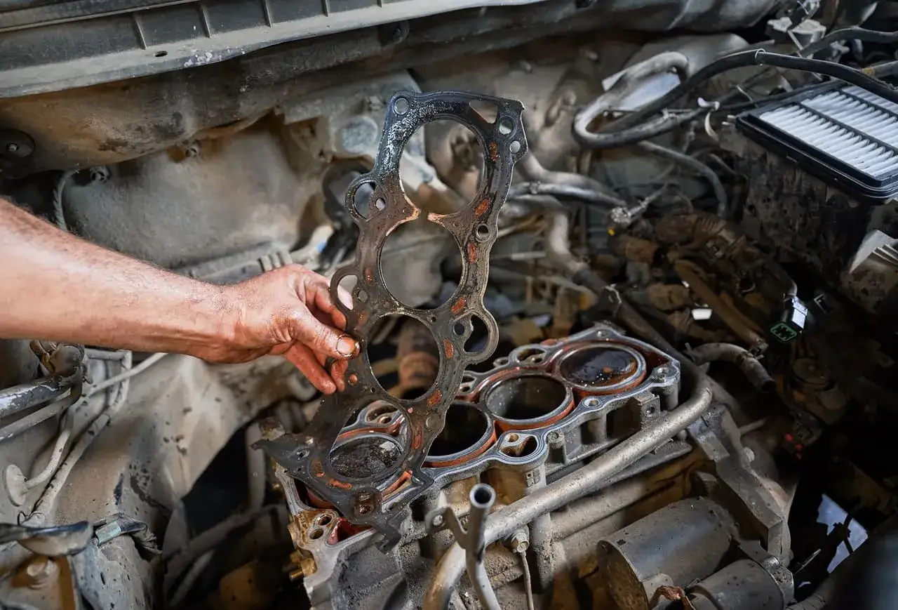 Mechaniker h&auml;lt alte Zylinderkopfdichtung. Kosten f&uuml;r den Wechsel der Zylinderkopfdichtung sind oft hoch.