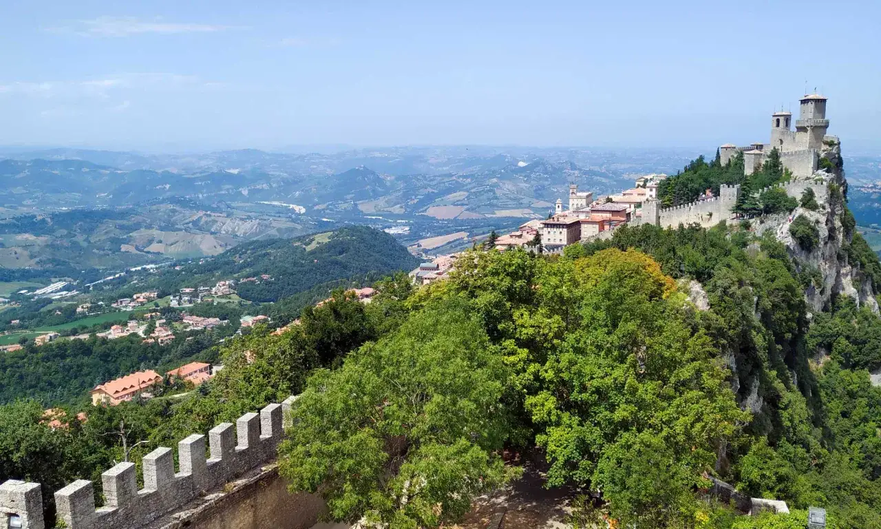 Vista panoramica di San Marino, con le sue torri medievali arroccate su un monte, che domina la campagna circostante fino a Rimini.