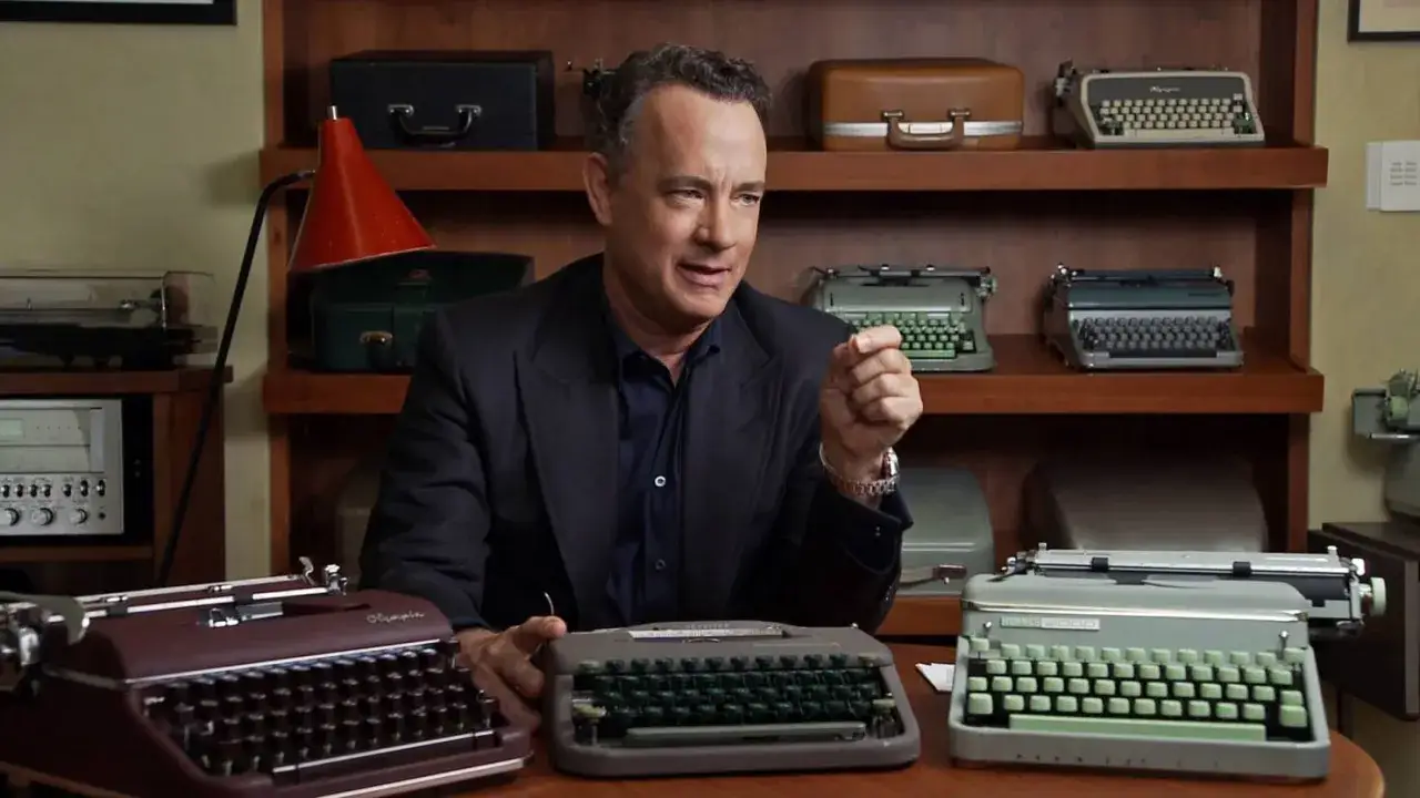 Tom Hanks opowiada, dlaczego znany aktor kolekcjonuje stare maszyny do pisania. Na stole i półkach widać wiele zabytkowych modeli.