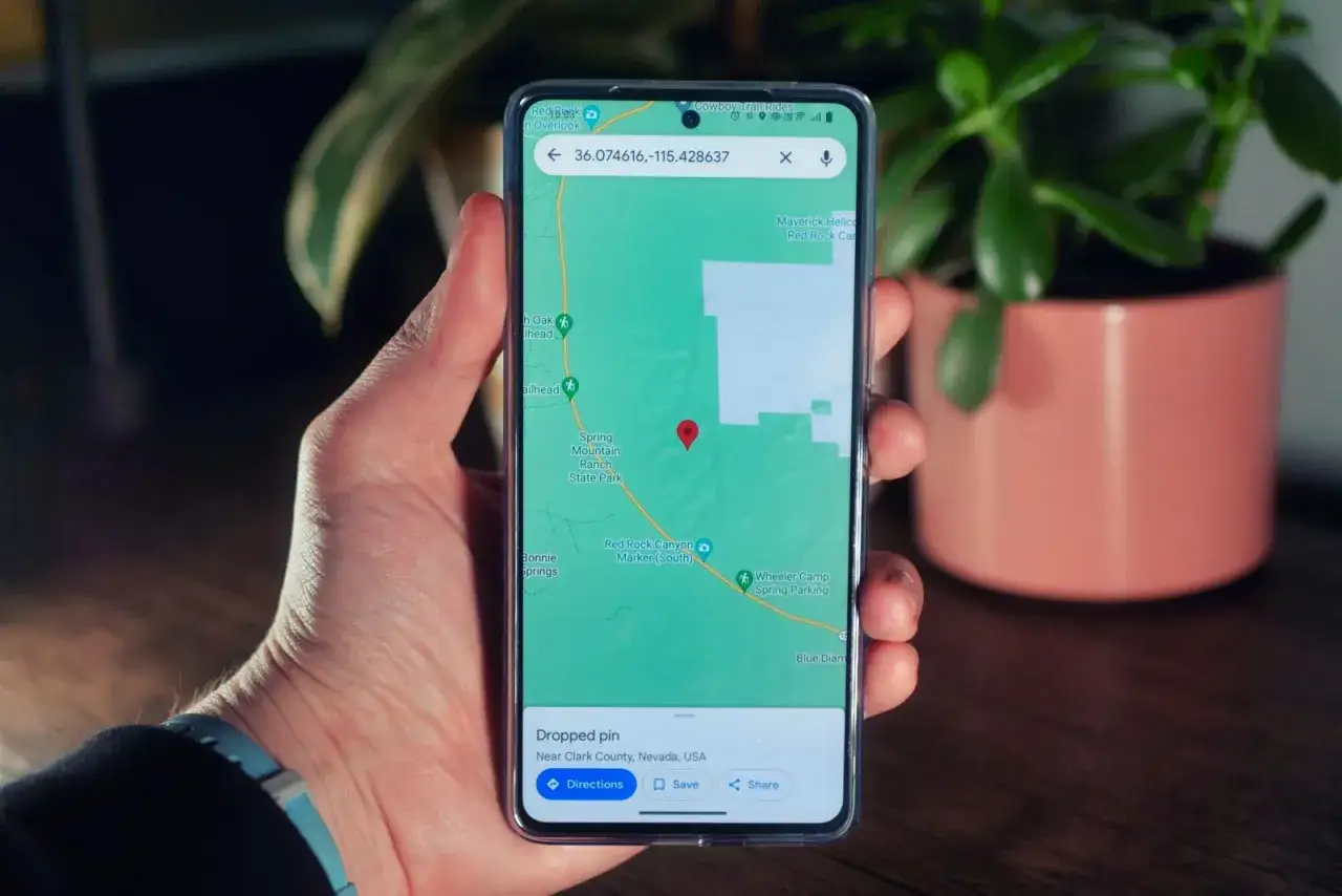 Dłoń trzyma telefon z mapą i czerwoną pinezką. Możesz wyślij pinezkę z lokalizacją do znajomych.