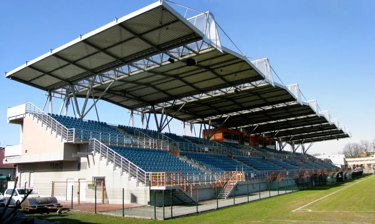 Nowoczesny stadion Siarki Tarnobrzeg z zadaszonymi trybunami i zieloną murawą.