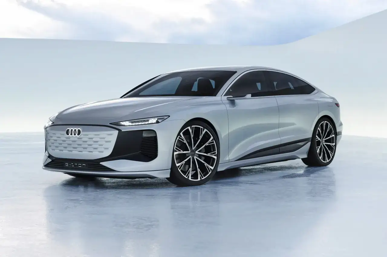 Srebrny Audi A6 e-tron, futurystyczny sedan z eleganckimi liniami i charakterystycznym grillem, prezentuje się na białym tle.