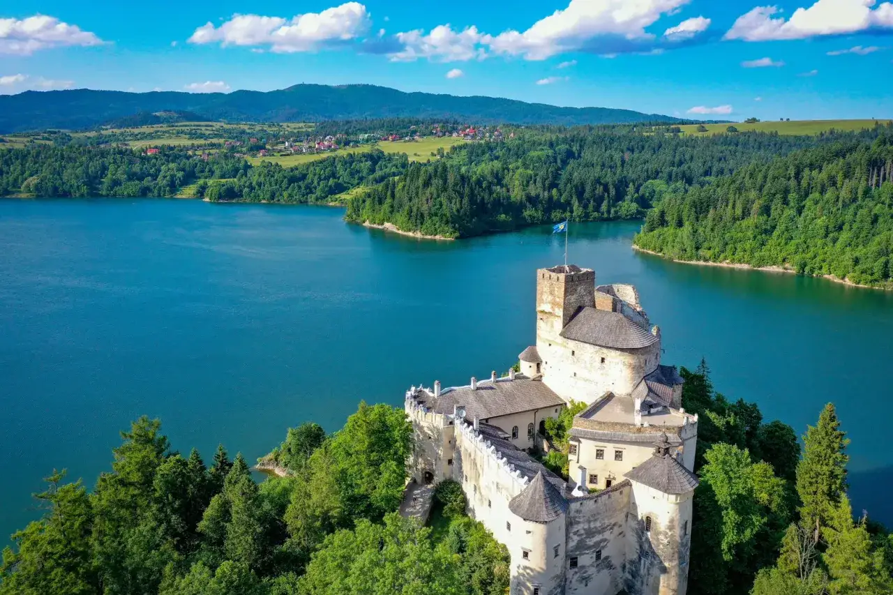 Zamek w Czorsztynie, niedzica, majestatycznie wznosi się nad turkusowym jeziorem, otoczony zielonymi lasami i górami.