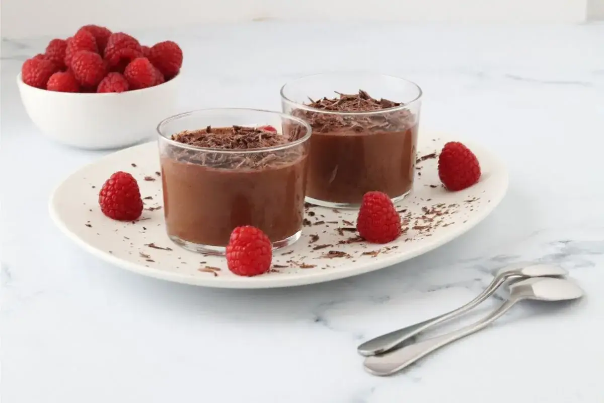 Deux verrines de mousse au chocolat 2 ingrédients sans oeuf, garnies de copeaux de chocolat et de framboises fraîches.