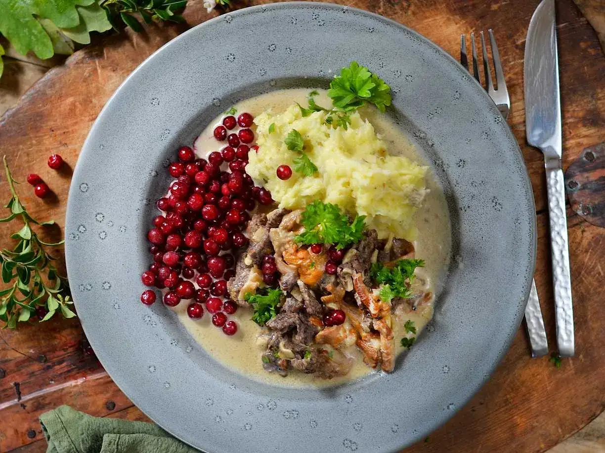 En tallrik med renskavsgryta, kr&auml;migt potatismos och f&auml;rska lingon. En klassisk svensk r&auml;tt som smakar sommar.