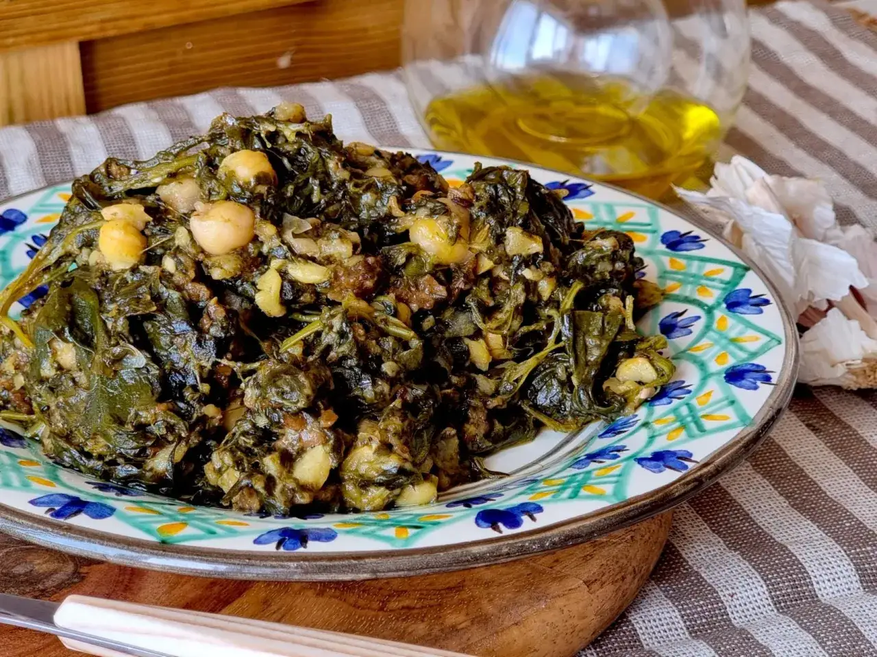 Un plato de garbanzos con espinacas, cocinado con ajo y aceite de oliva, servido en una vajilla colorida.