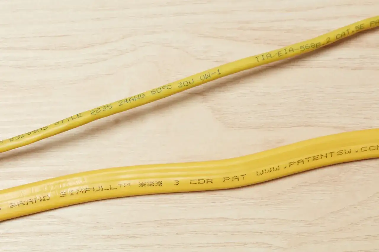 Żółte kable sieciowe z oznaczeniami, które pomagają zrozumieć, jak czytać oznaczenia kabli: TIA/EIA-568B.2 CAT.5E, 24AWG, 60°C.