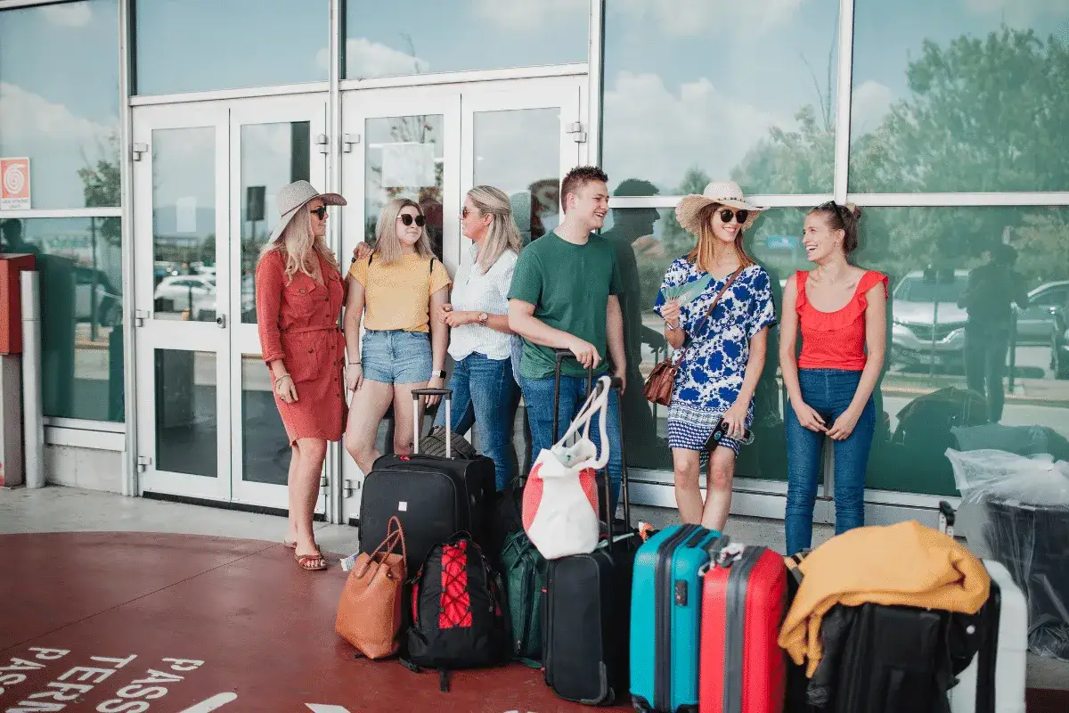 Grupa przyjaciół z bagażami czeka na lotnisku. Wszyscy są podekscytowani podróżą na Maltę.