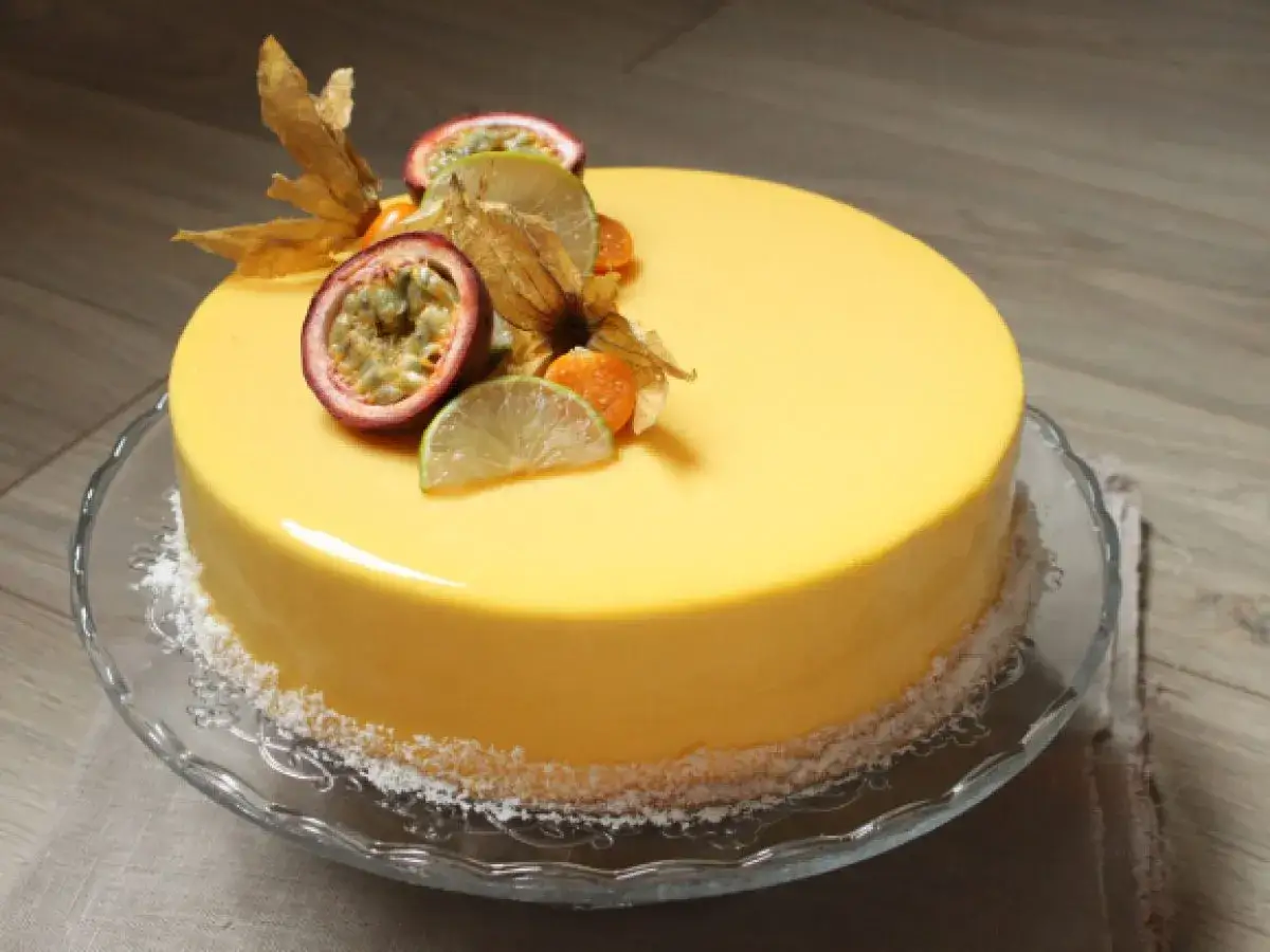 Gâteau jaune vif, décoré de quartiers de fruit de la passion, de physalis et de fines tranches de citron vert.