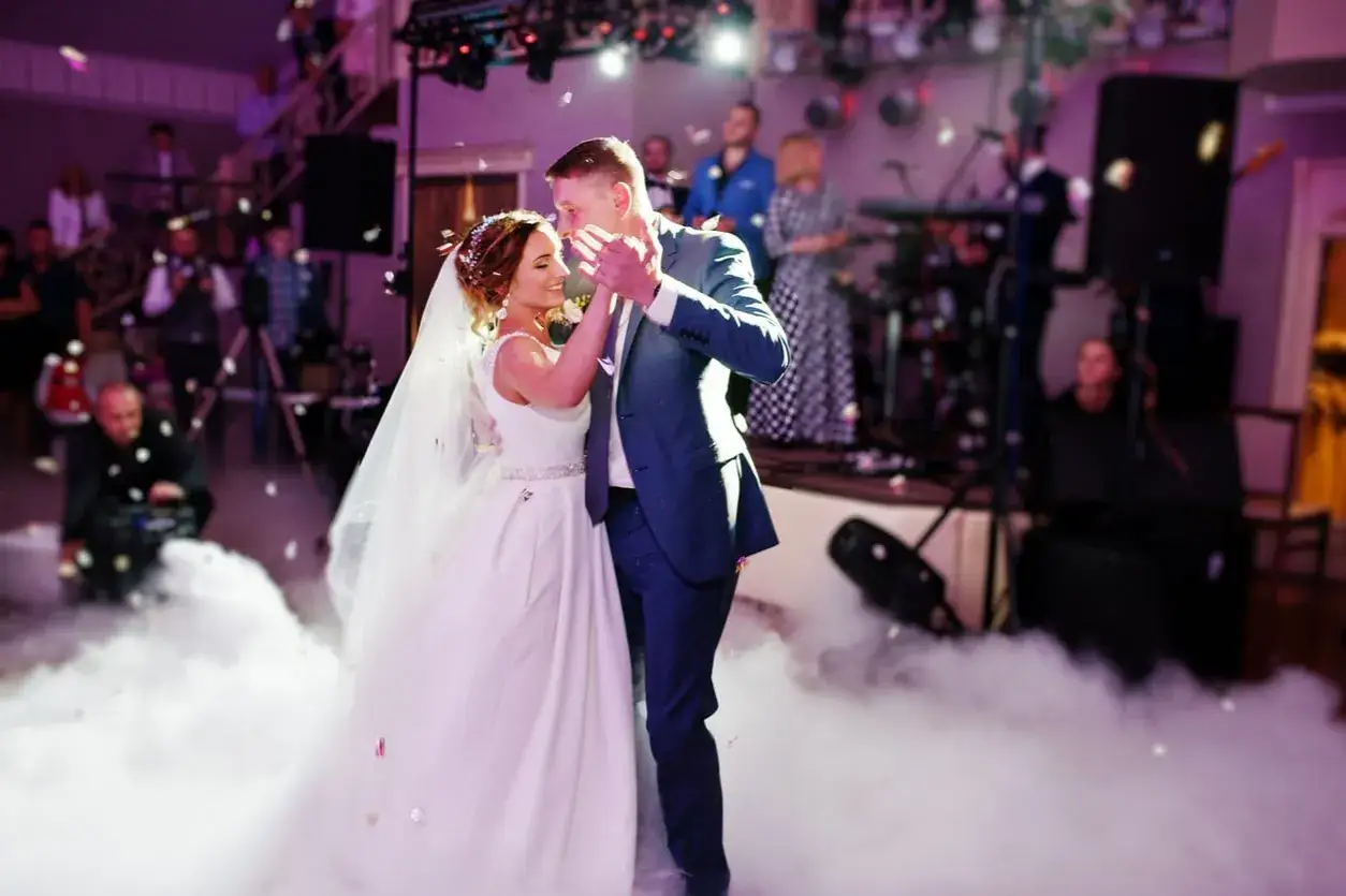 Un couple danse lors de l'ouverture de bal de leur mariage, entour&eacute; de fum&eacute;e et de confettis.