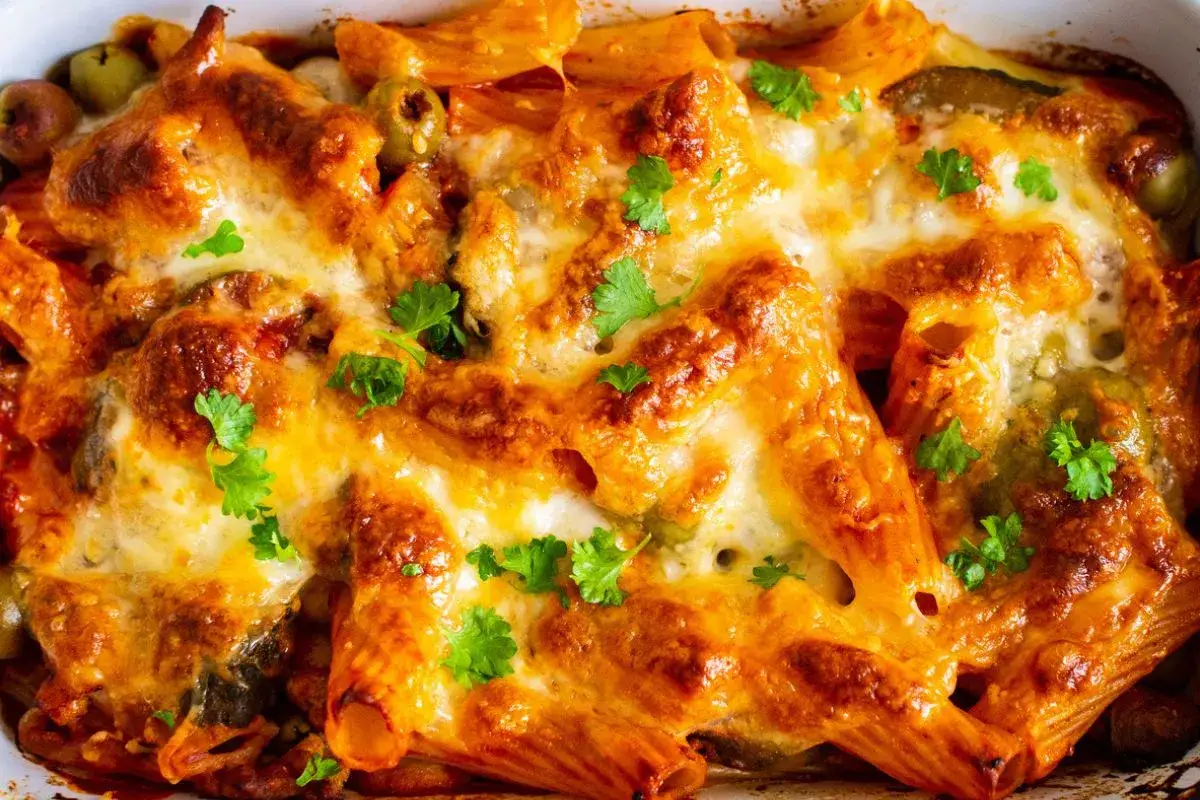 Un invitante pasta al forno con formaggio fuso, olive verdi e prezzemolo fresco.