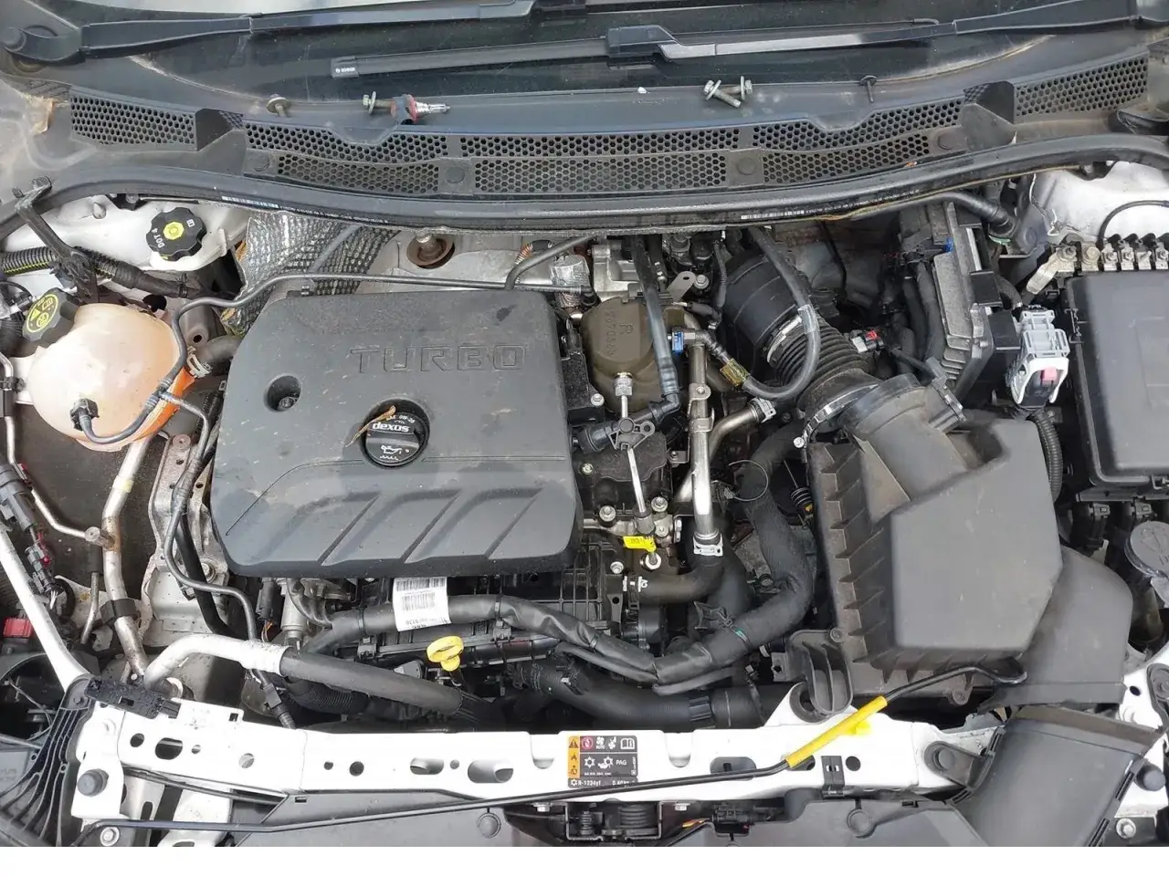 Silnik Opel Astra Turbo z widocznym napisem TURBO na pokrywie. Widać elementy układu dolotowego i chłodzenia.