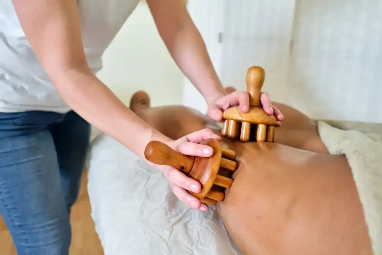 Masajeador de madera trabajando en las piernas, ayudando a tratar diferentes tipos de celulitis.
