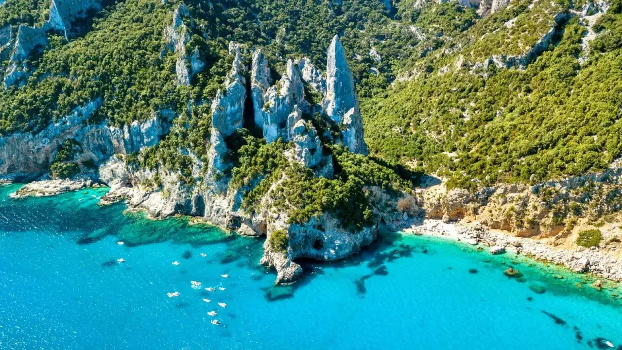 Falaises verdoyantes et pics rocheux spectaculaires en Sardaigne. Une invitation à la randonnée et à la découverte de criques aux eaux turquoise.