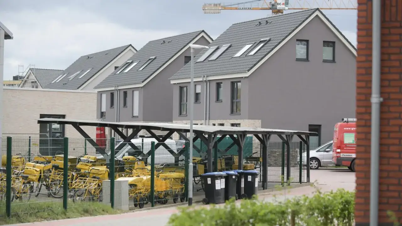 Reihenhäuser in Moers mit vielen gelben Lastenrädern unter einem Carport. Ein roter Lieferwagen steht daneben.