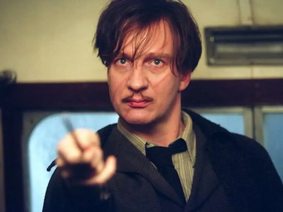 Remus Lupin z bliznami na twarzy, w eleganckim stroju, z różdżką w dłoni, gotów do walki.