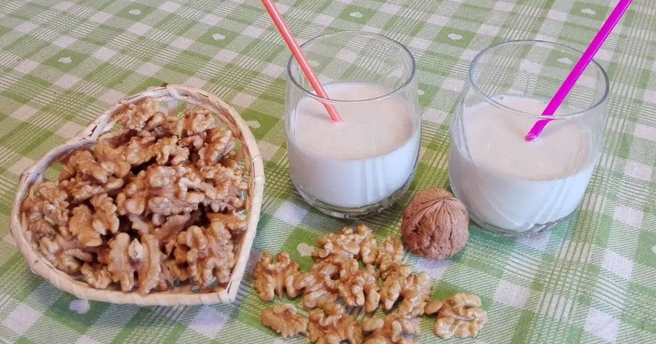 Due bicchieri con latte di noci fatto in casa e una ciotola a forma di cuore piena di noci.