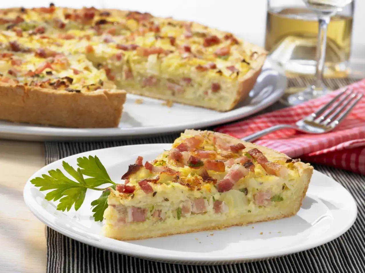 Ein St&uuml;ck herzhafter Speckkuchen, inspiriert von ewiger Kohl Rezepte, auf einem Teller mit Petersilie garniert.