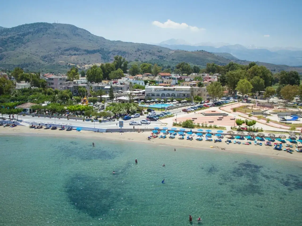 Ein **epos luxury beach hotel** mit Pool und vielen Liegen am Sandstrand, umgeben von gr&uuml;nen H&uuml;geln und blauem Meer.