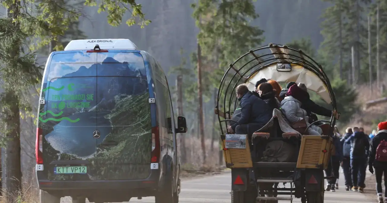 Morskie Oko: cennik meleksy. Turystów w wozie ciągnie meleks, obok jedzie bus z widokiem na góry.