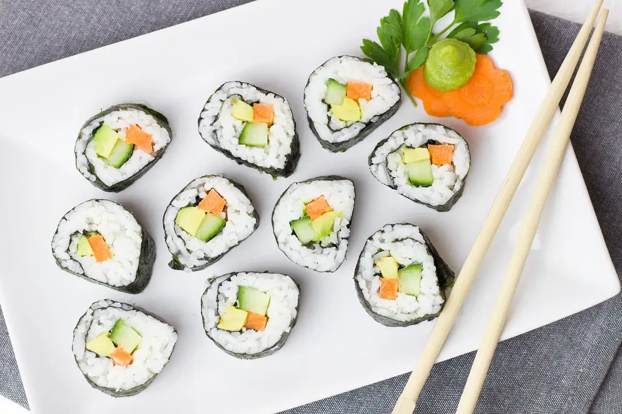 Na talerzu ułożono 10 sztuk sushi z awokado, og&oacute;rkiem i marchewką. Idealna porcja, by zastanowić się, ile sztuk sushi na osobę zjeść.
