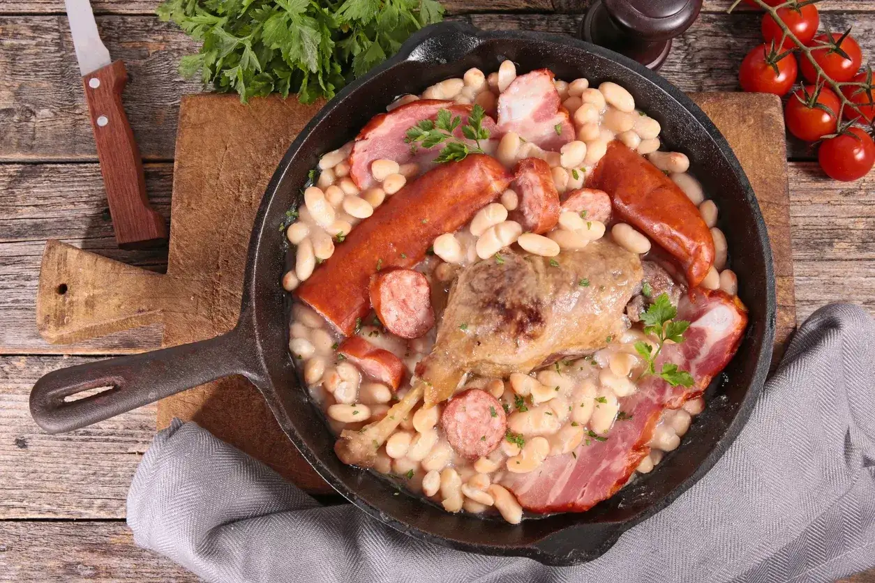 Un plat mijoté de haricots blancs, saucisses, confit de canard et lardons, parfait pour la recette du vrai cassoulet traditionnel.