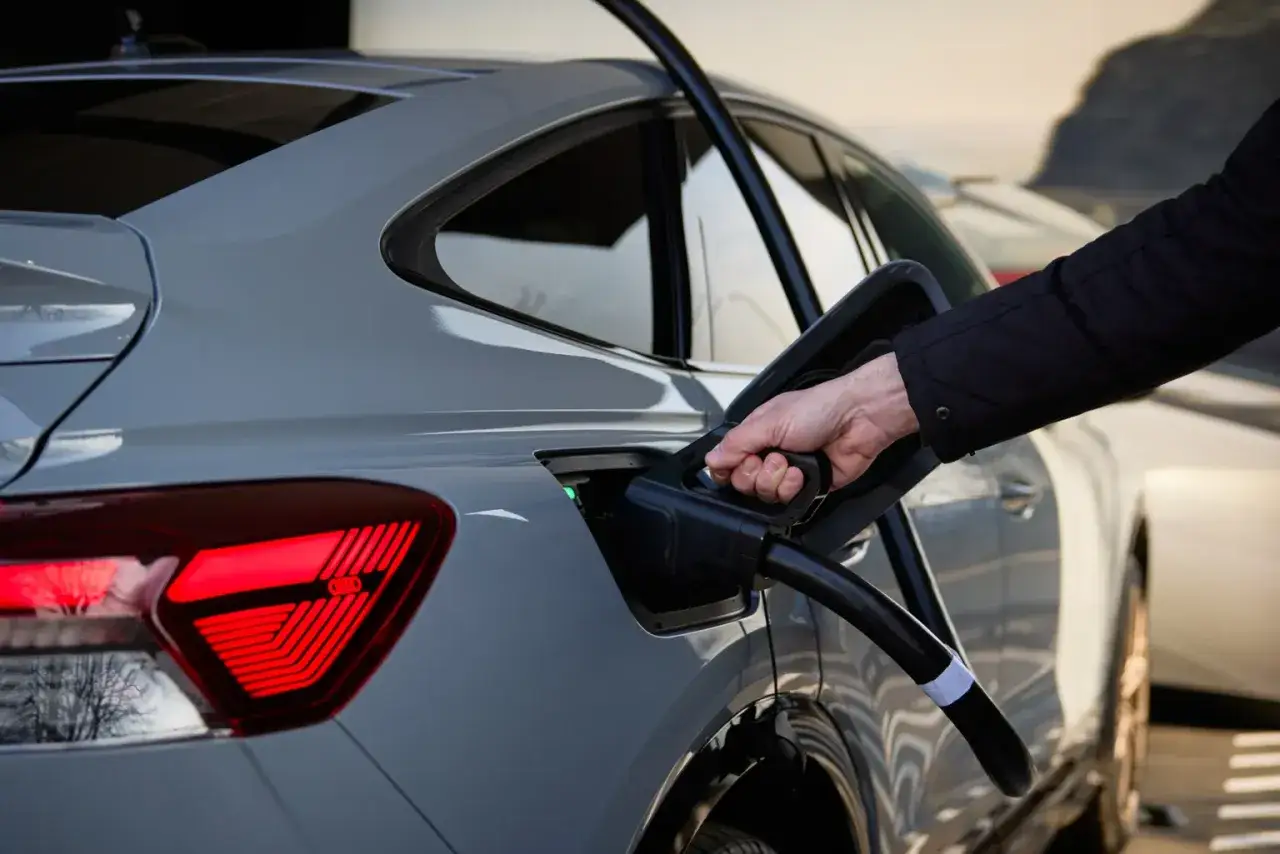 Ręka podłącza ładowarkę do samochodu elektrycznego. To część mojego elektryka, który dba o środowisko.
