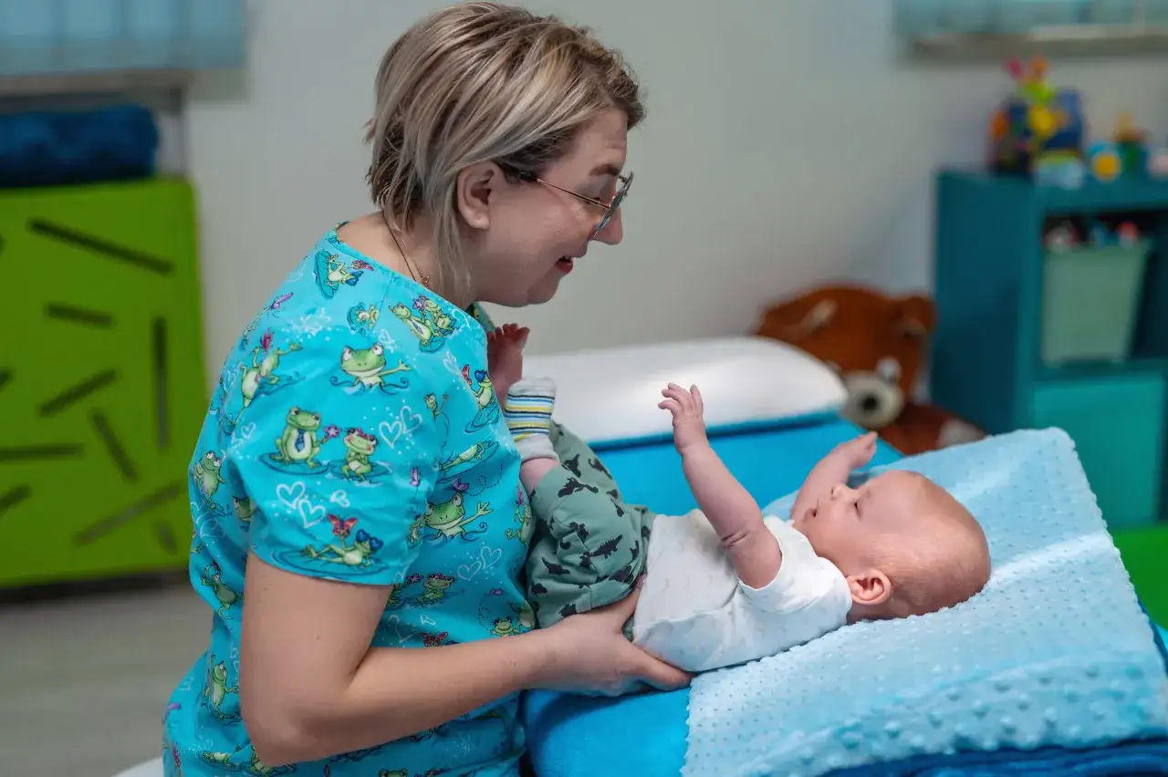 Kobieta w piżamie z żabkami delikatnie układa dziecko do snu. Nawet gdy ulewa, maluch czuje się bezpiecznie.