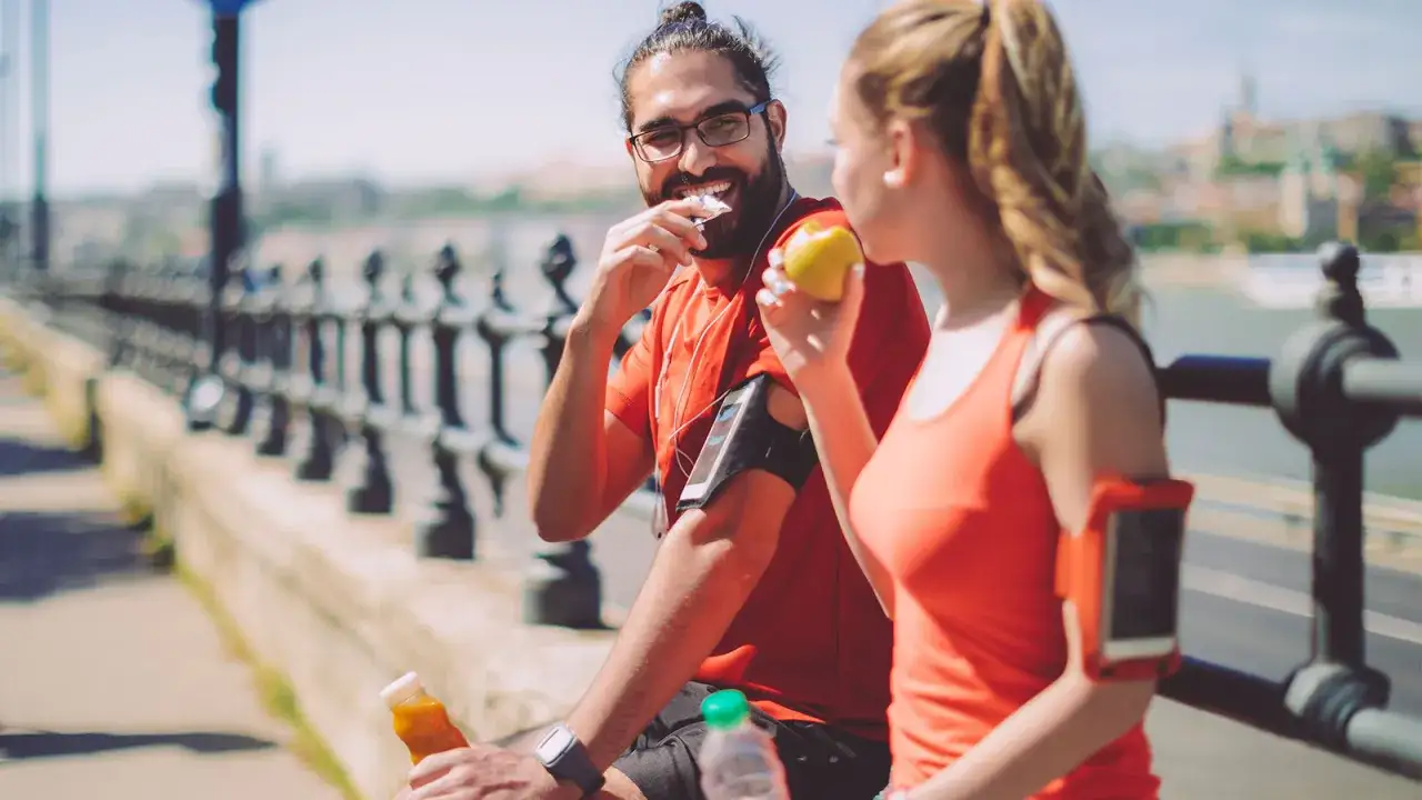 Glückliches Paar isst vor oder nach dem Sport einen Apfel und trinkt Saft.