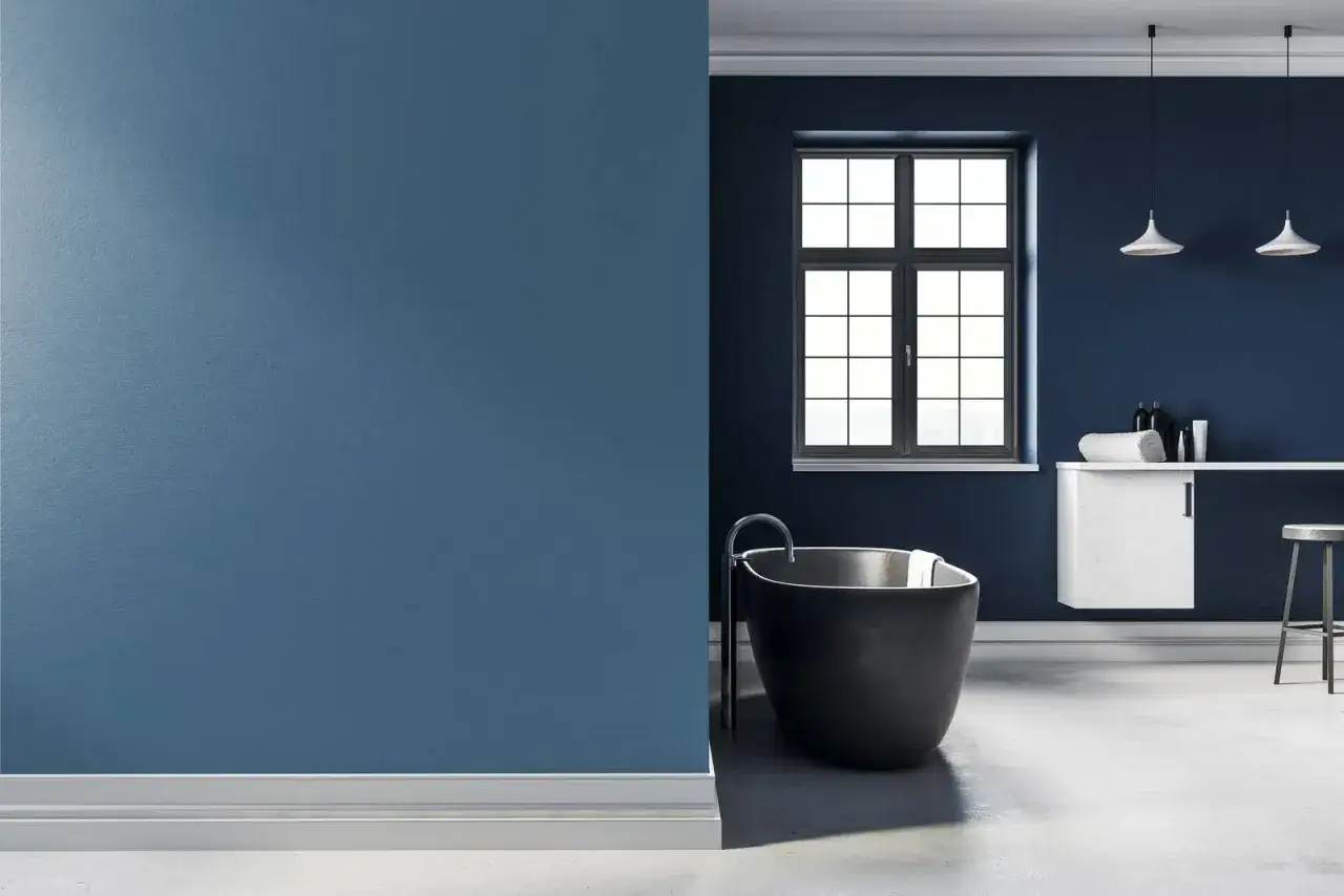 Bagno moderno con vasca nera e pareti blu intenso, un esempio di come le ppg vernici trasformano gli spazi.