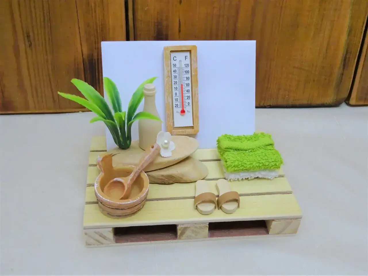 Miniatur-Sauna mit Thermometer, Aufgusseimer, Handtüchern und Pantoffeln. Perfekt als **Sauna Gutschein** für Entspannung.