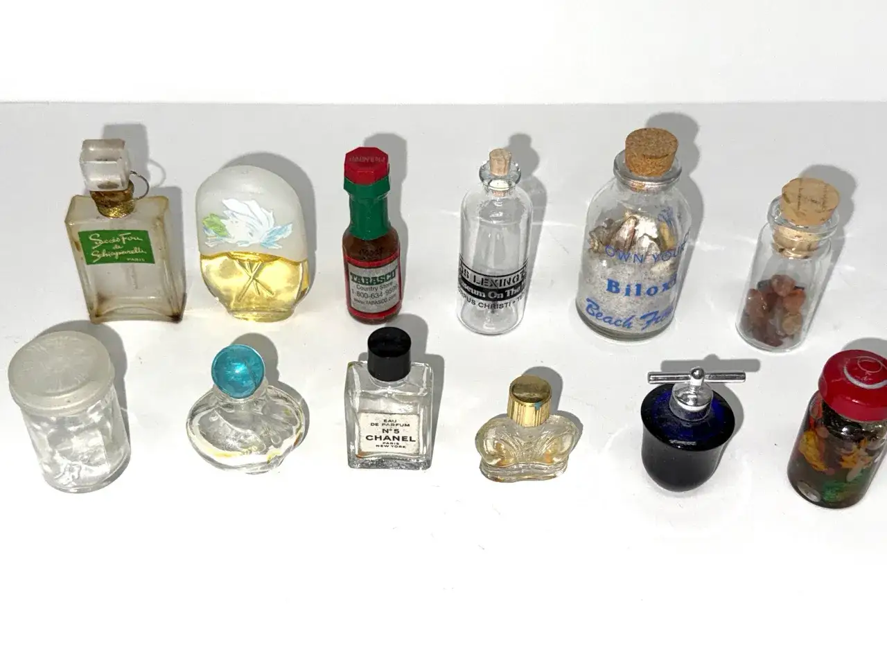 Kolekcja miniaturowych perfum z lat 2000. Znajdują się tu flakoniki Chanel N°5, Schiaparelli i inne, tworząc nostalgiczny klimat.
