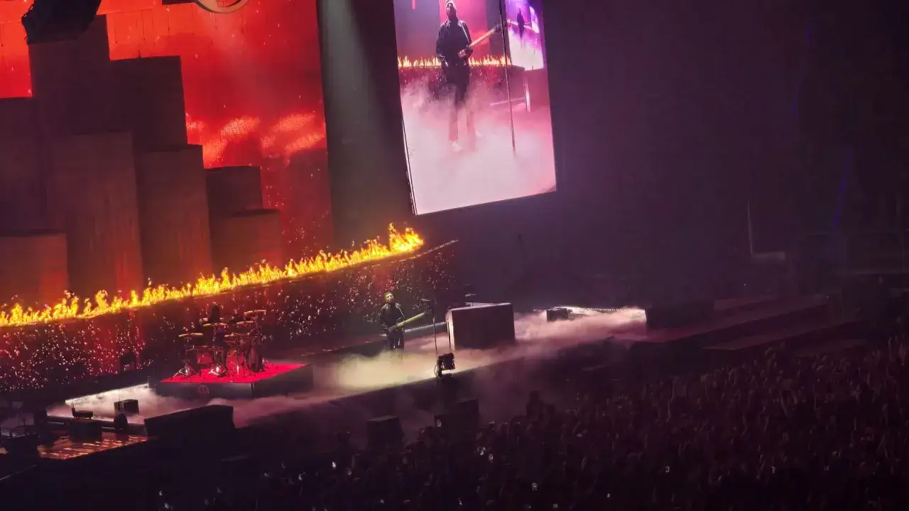 Niesamowite twenty one pilots koncerty! Płonąca scena, dym i tłum w ekstazie. Tyler Joseph gra na gitarze, a za nim perkusja.