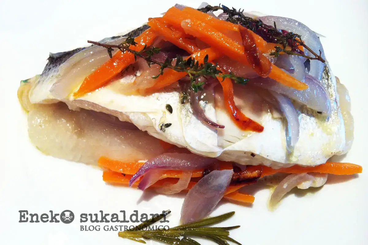 Lubina en papillote con zanahoria y cebolla morada, perfumada con hierbas aromáticas. Un plato ligero y sabroso.