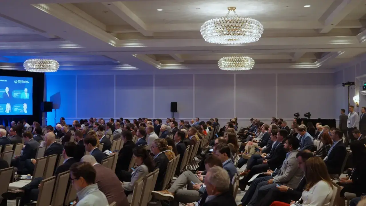 Attendees listen intently at the Morgan Stanley Laguna Conference, a large gathering in a well-lit ballroom with ornate chandeliers.