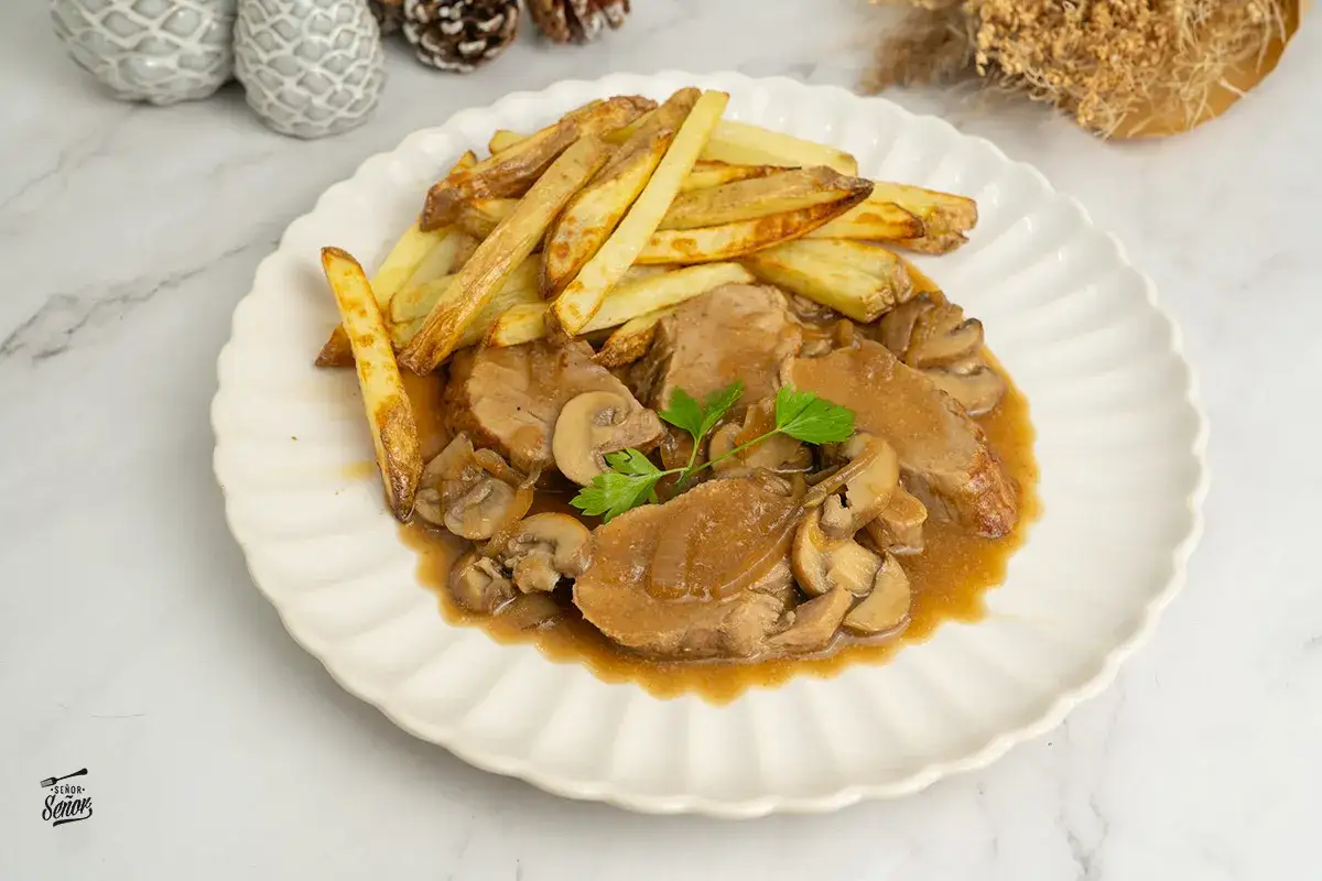 Solomillo en salsa de la abuela con champiñones y patatas fritas crujientes. Un plato casero que evoca recuerdos.