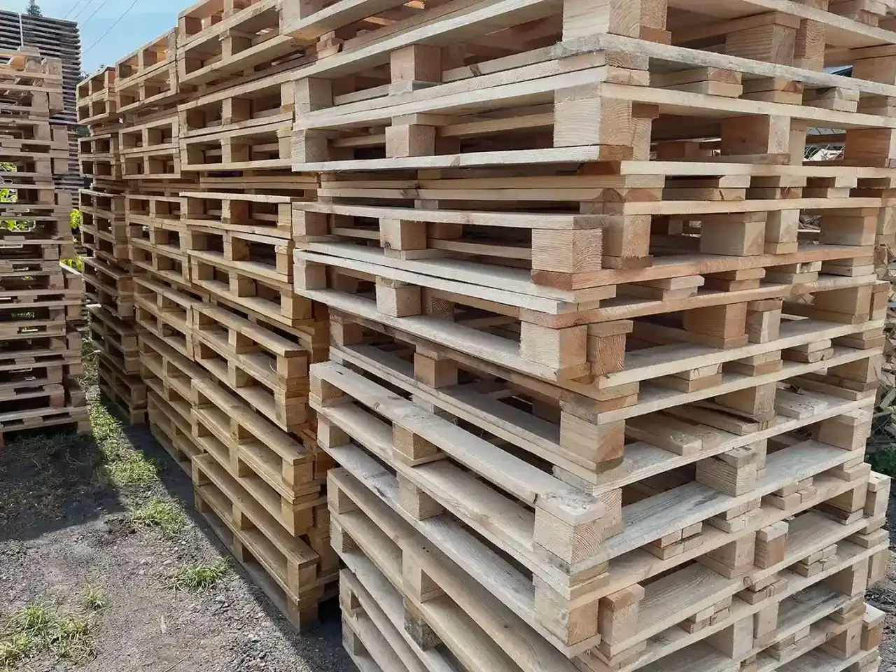 Stosy drewnianych palet czekają na transport. Dowiedz się, jak układać drewno na palecie, by było stabilne i bezpieczne.