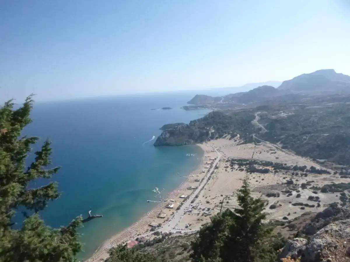 Widok z góry na piaszczystą plażę Tsambika z turkusową wodą i górami w tle.