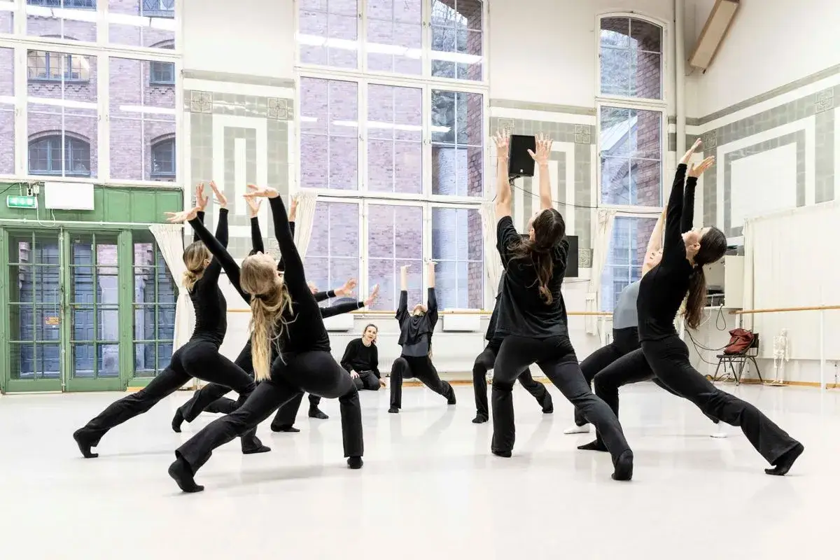 Dansare i svarta kl&auml;der &ouml;var en koreografi i en ljus studio. Moderna dansteatern &auml;r en plats f&ouml;r kreativitet och r&ouml;relse.