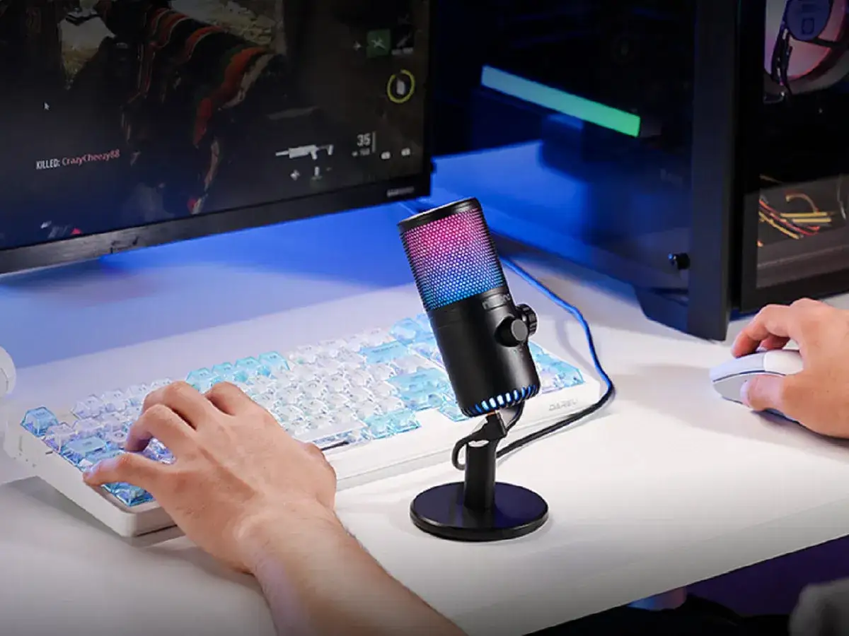 Gaming-Setup mit beleuchtetem Mikrofon für PC-Tests. Hände tippen auf Tastatur, Maus bereit.