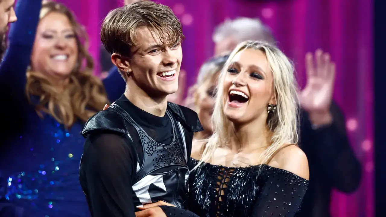 Glada vinnare av Let's Dance, en ung man och kvinna i glittrande scenkläder, skrattar hjärtligt.
