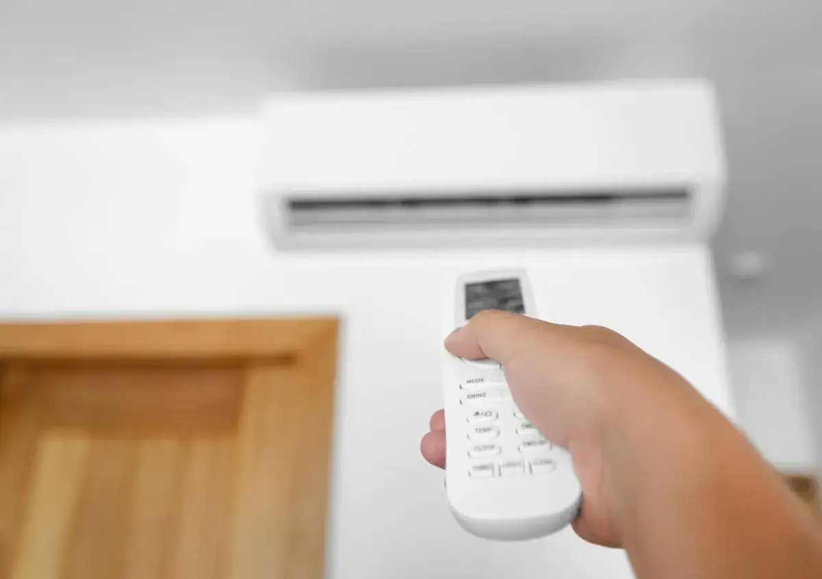 Mano che regola la temperatura condizionatore aria fredda estate con telecomando. L'aria fresca porta sollievo.