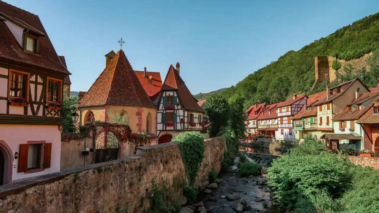 Urokliwa wioska w Alzacji i Lotaryngii, z kolorowymi domami i strumieniem.