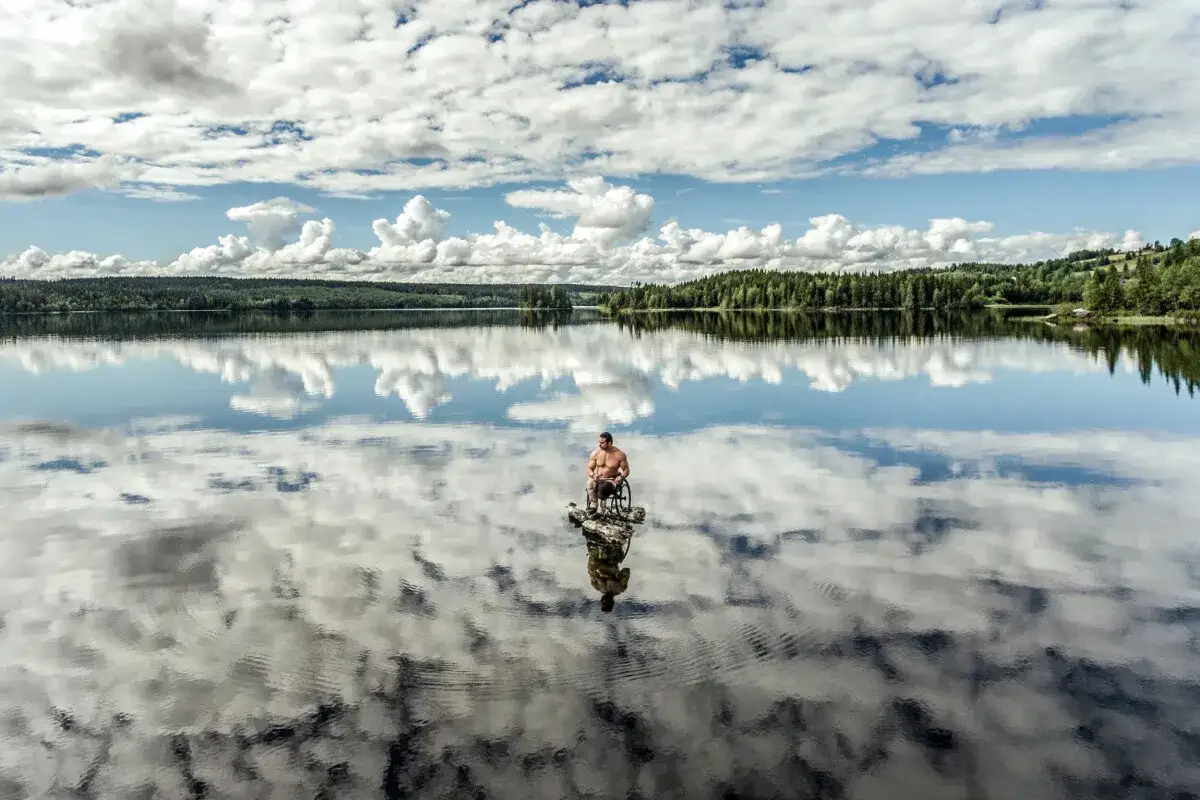 En man i rullstol sitter p&aring; en sten ute p&aring; en spegelblank sj&ouml;. Solen lyser p&aring; den molniga himlen. Sophie Odelberg f&aring;ngar en stund av lugn.
