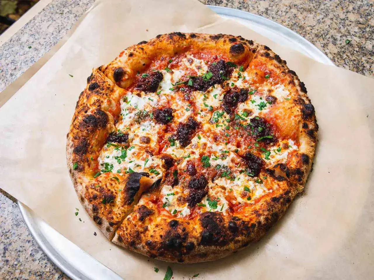 Pikantna pizza z ndują, która to jest? Gorąca, z ciągnącym serem i chrupiącym ciastem, posypana natką pietruszki.