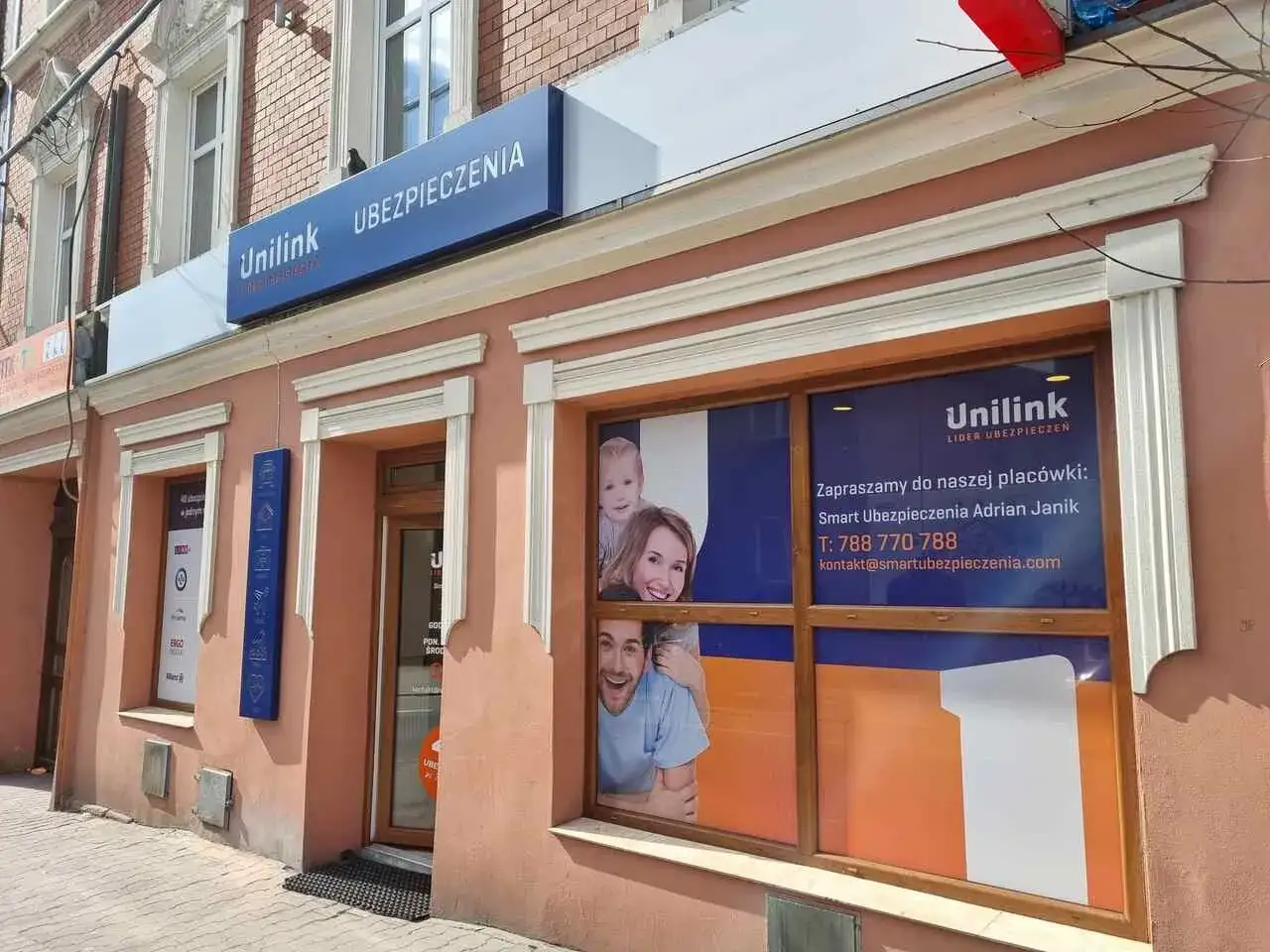 Elewacja biura ubezpieczeniowego Unilink z banerem i reklamą na szybie.