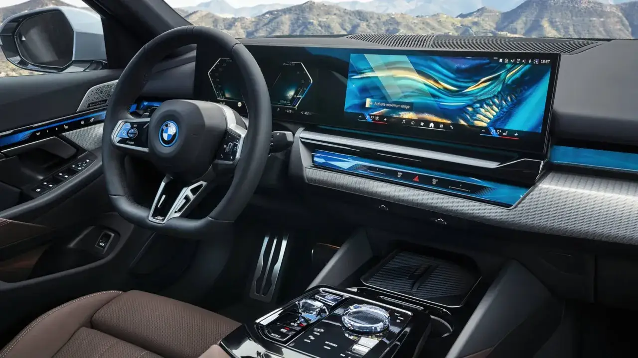 Wnętrze BMW 550e z dużym ekranem multimedialnym i cyfrowymi zegarami.