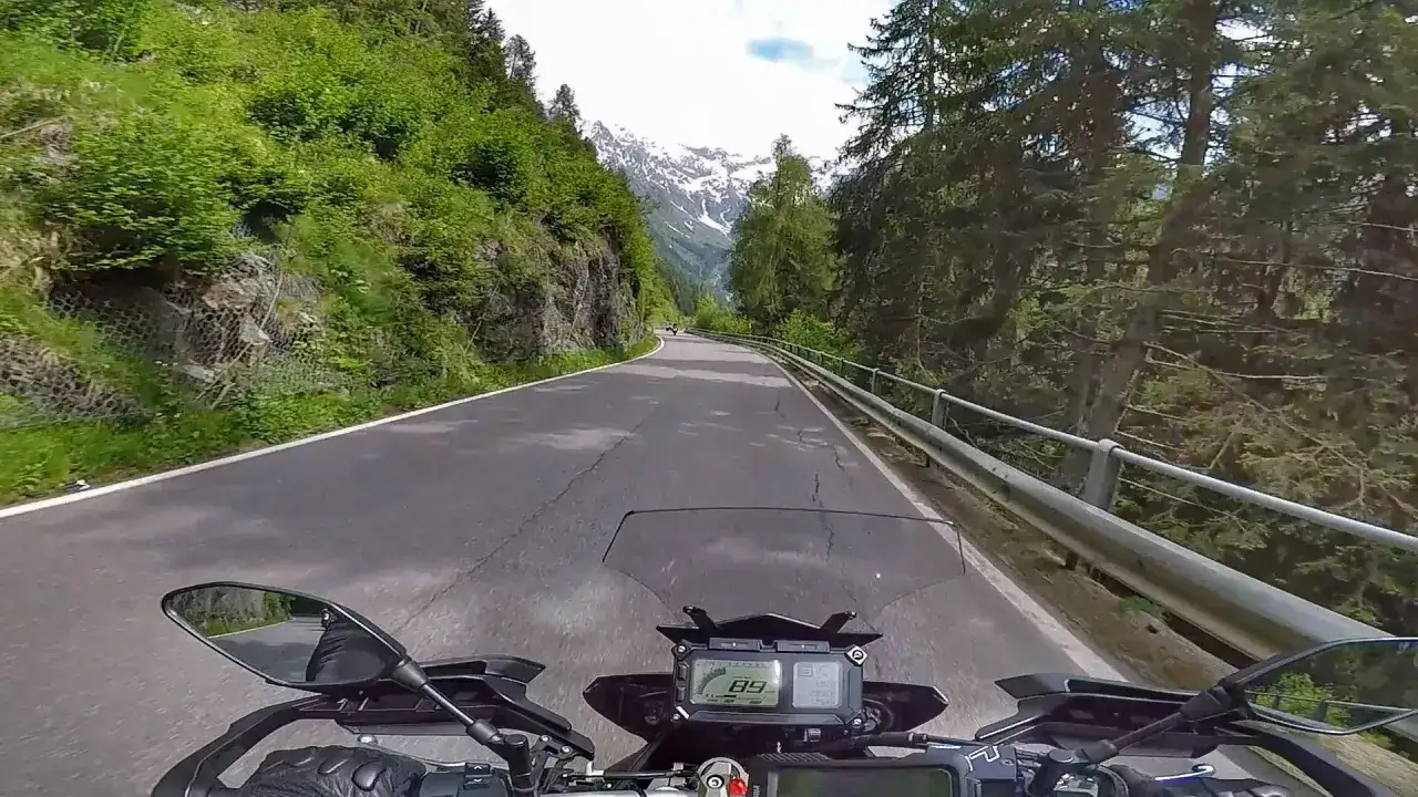 In sella alla moto, la strada serpeggia verso le cime innevate. Un'avventura sul Passo del Tonale, tra boschi e panorami mozzafiato.
