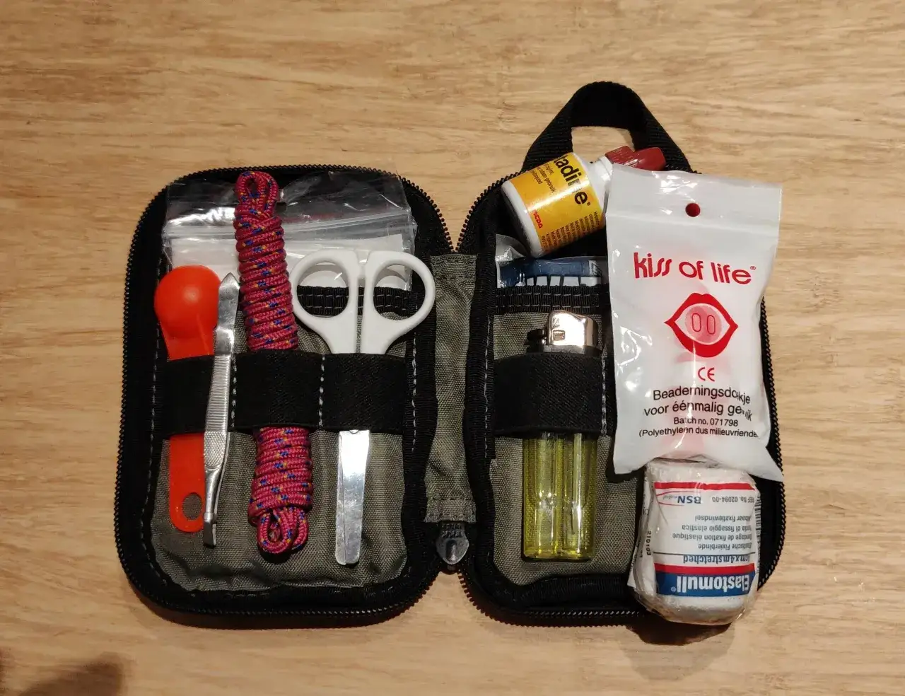 Kit de primeros auxilios compacto, ideal para tu edc urbano. Incluye pinzas, tijeras, cuerda, encendedor y suministros m&eacute;dicos.