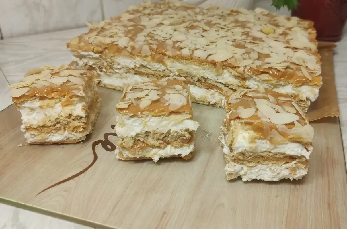 Pyszne ciasto na krakersach z kremem i karmelem, posypane płatkami migdałów. Idealne na deser.